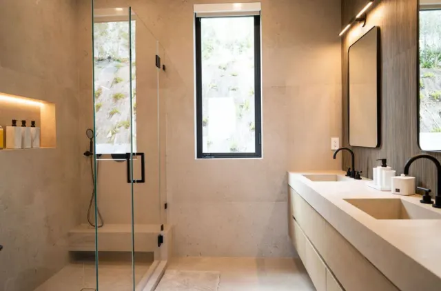 Bathroom with a glass shower, lit wall niche and a long floating vanity