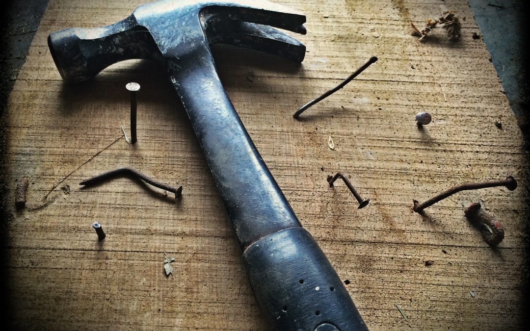 black claw hammer on a wooden plank with nails| how to prepare for a major home remodeling project