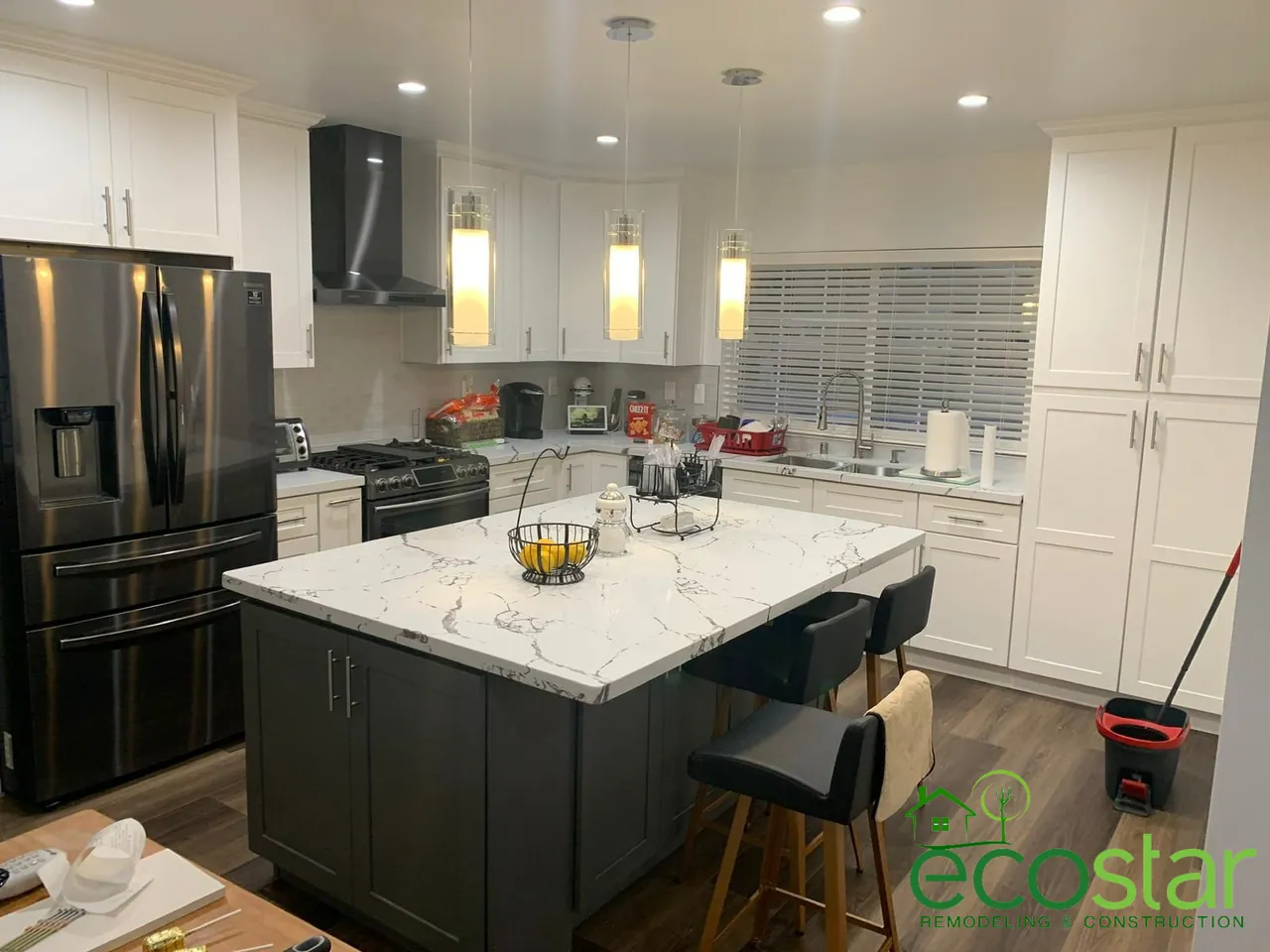 White kitchen with a gray island, quartz countertop and pendant lights, by EcoStar Remodeling & Construction